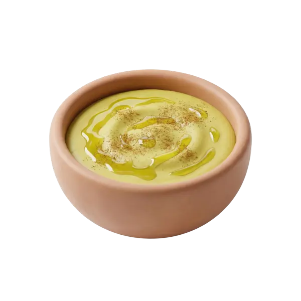 Close-up of a creamy green broad-bean dip drizzled with olive oil and sprinkled with ground spice, showing a smooth glossy texture. Served in a terracotta bowl on a solid black background.